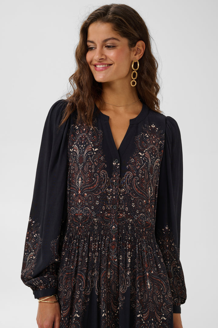 Cream Josia maxi dress, flowing fabric with floral pattern, sleeveless design, and fitted waist for elegant summer style.