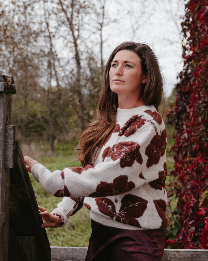 B.Young Manda floral knit sweater with colorful floral pattern, long sleeves, and cozy fit on a neutral background.
