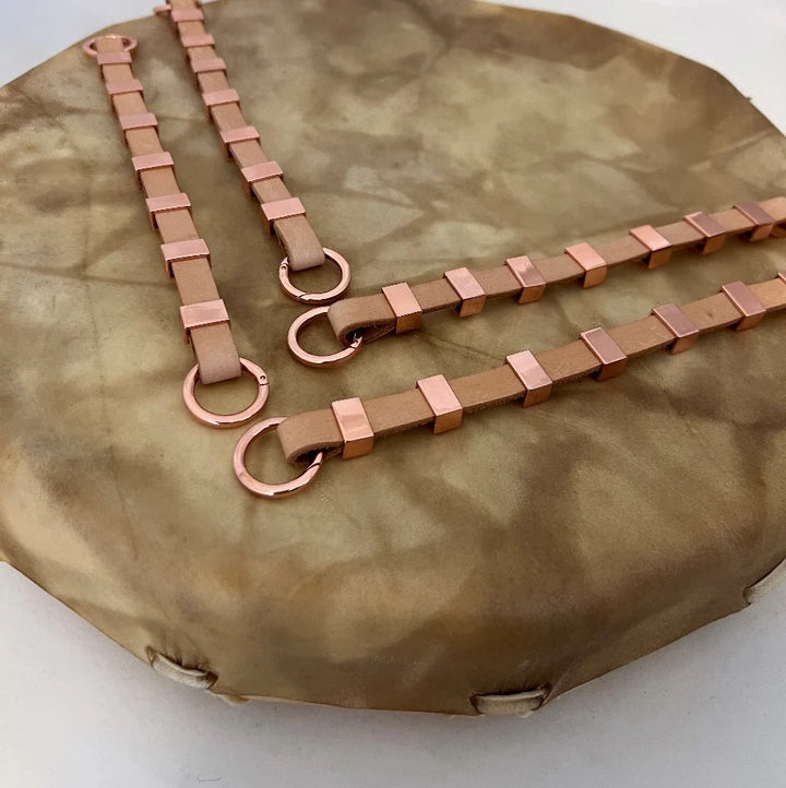 Two rose gold and natural leather bracelets  on a textured brown surface
