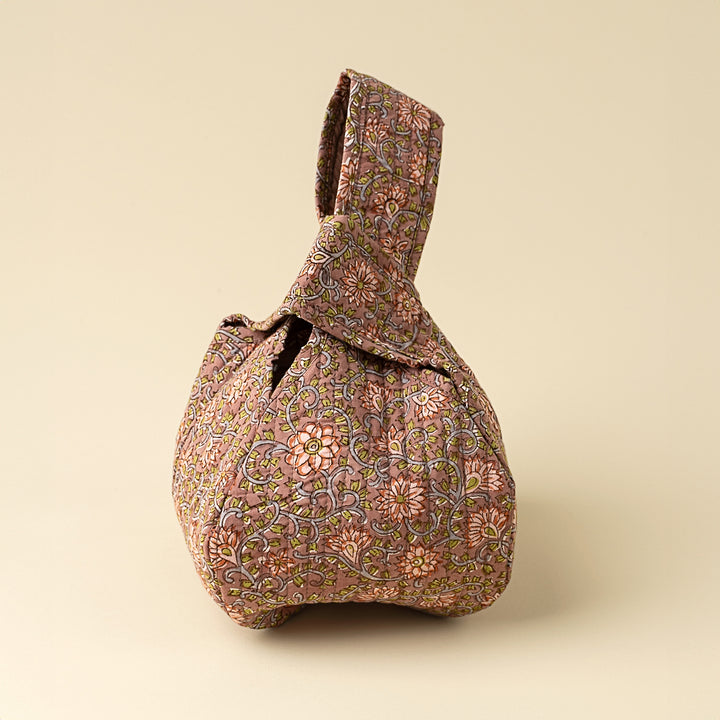 Indaba floral block print vanity pouch with knot closure, showcasing vibrant patterns and compact design for travel and organization.