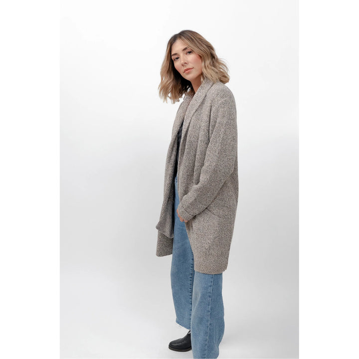 Woman wearing a gray cardigan and blue jeans on a white background