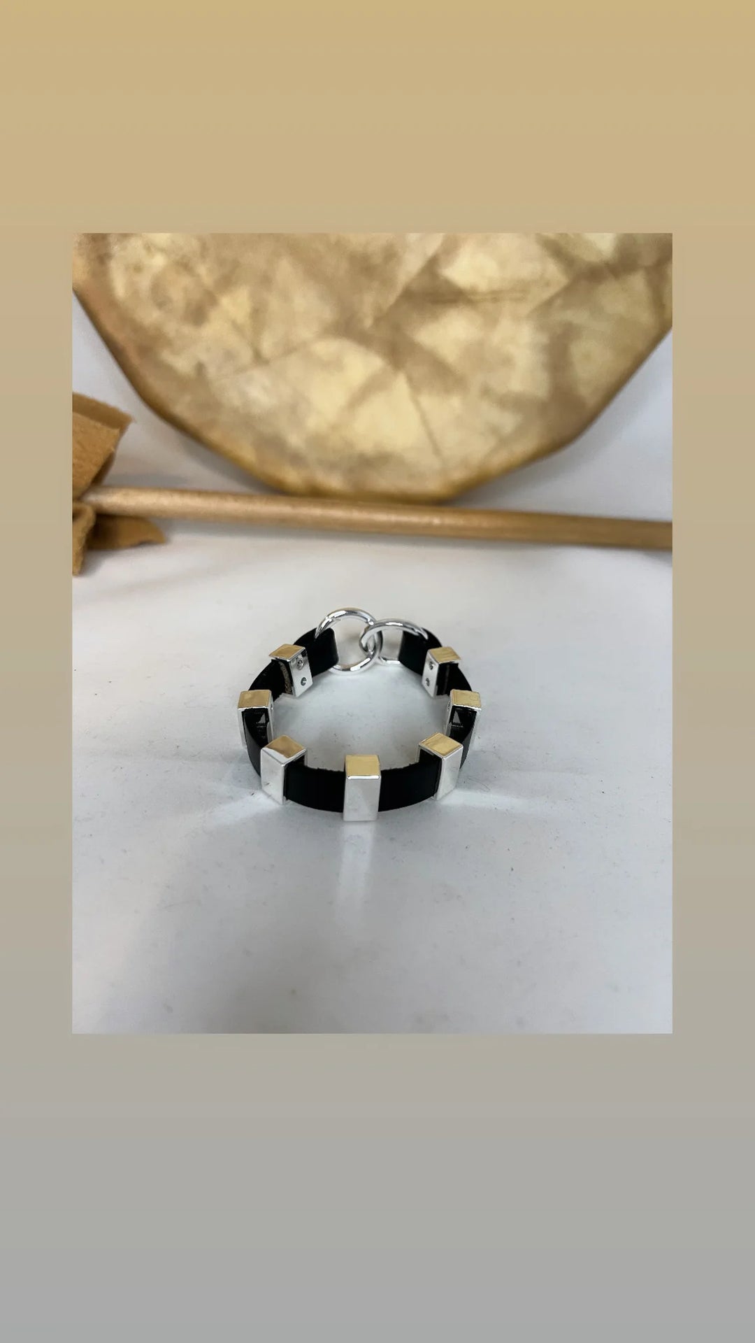 Black and gold ring on a white surface with a beige background