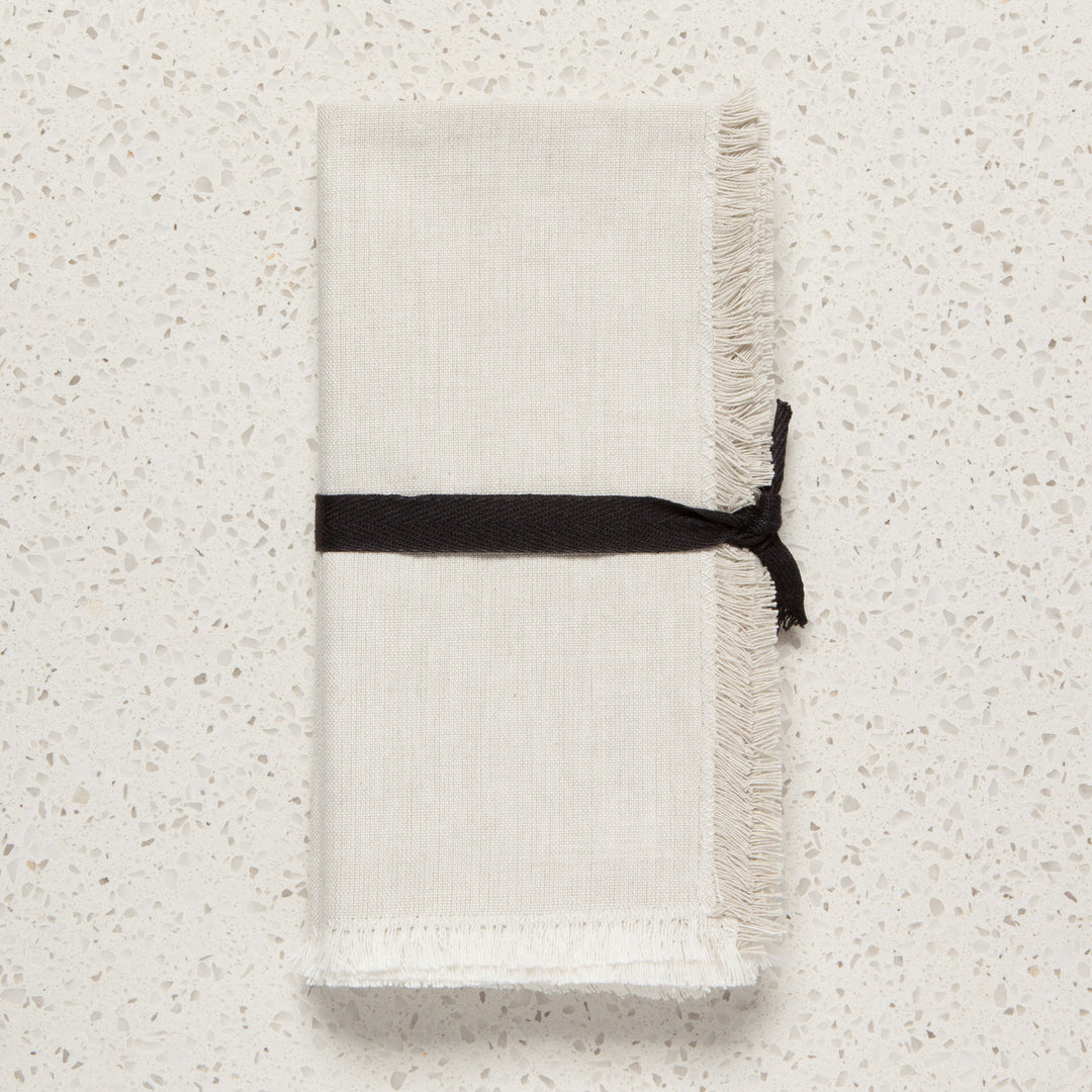 Pair of Danica chambray cotton table napkins folded on a dining table, showcasing soft fabric and elegant design.