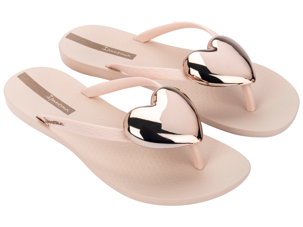 Beige flip-flops with metallic heart-shaped straps on a white background