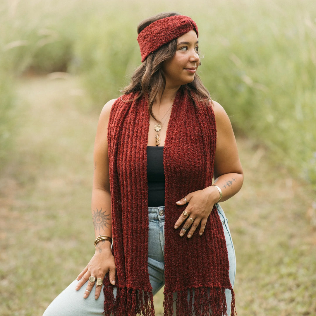 Woman wearing a red scarf and headband standing in a grassy field
