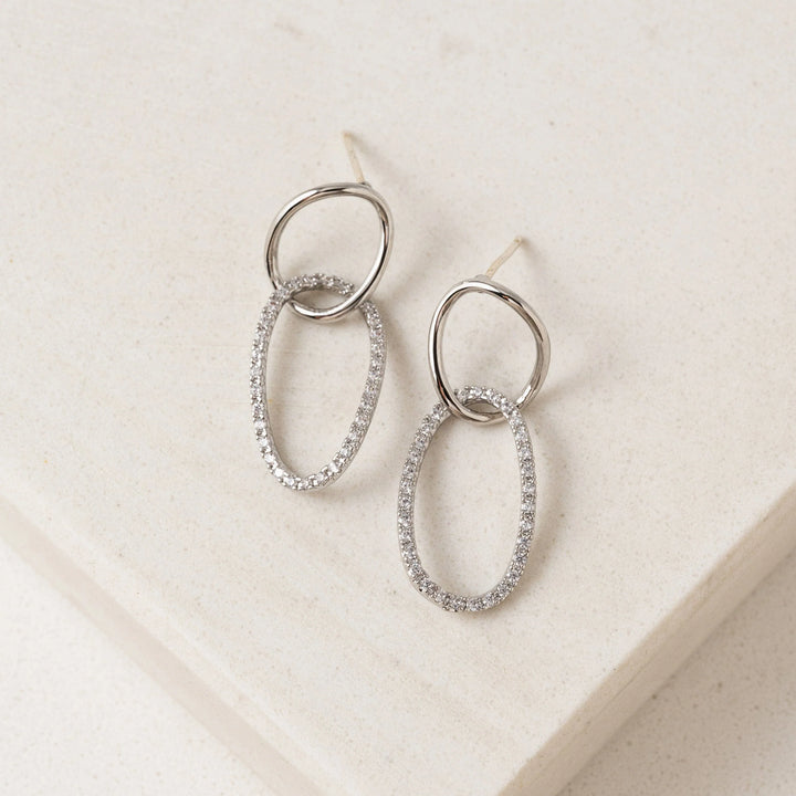 Pair of silver hoop earrings on a light beige background