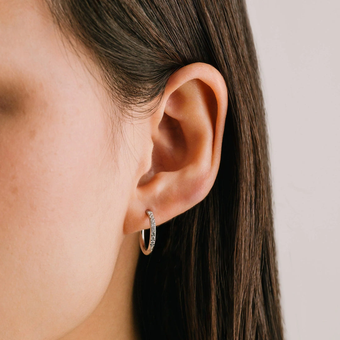 Close-up of an ear wearing a small hoop earring with a blurred background