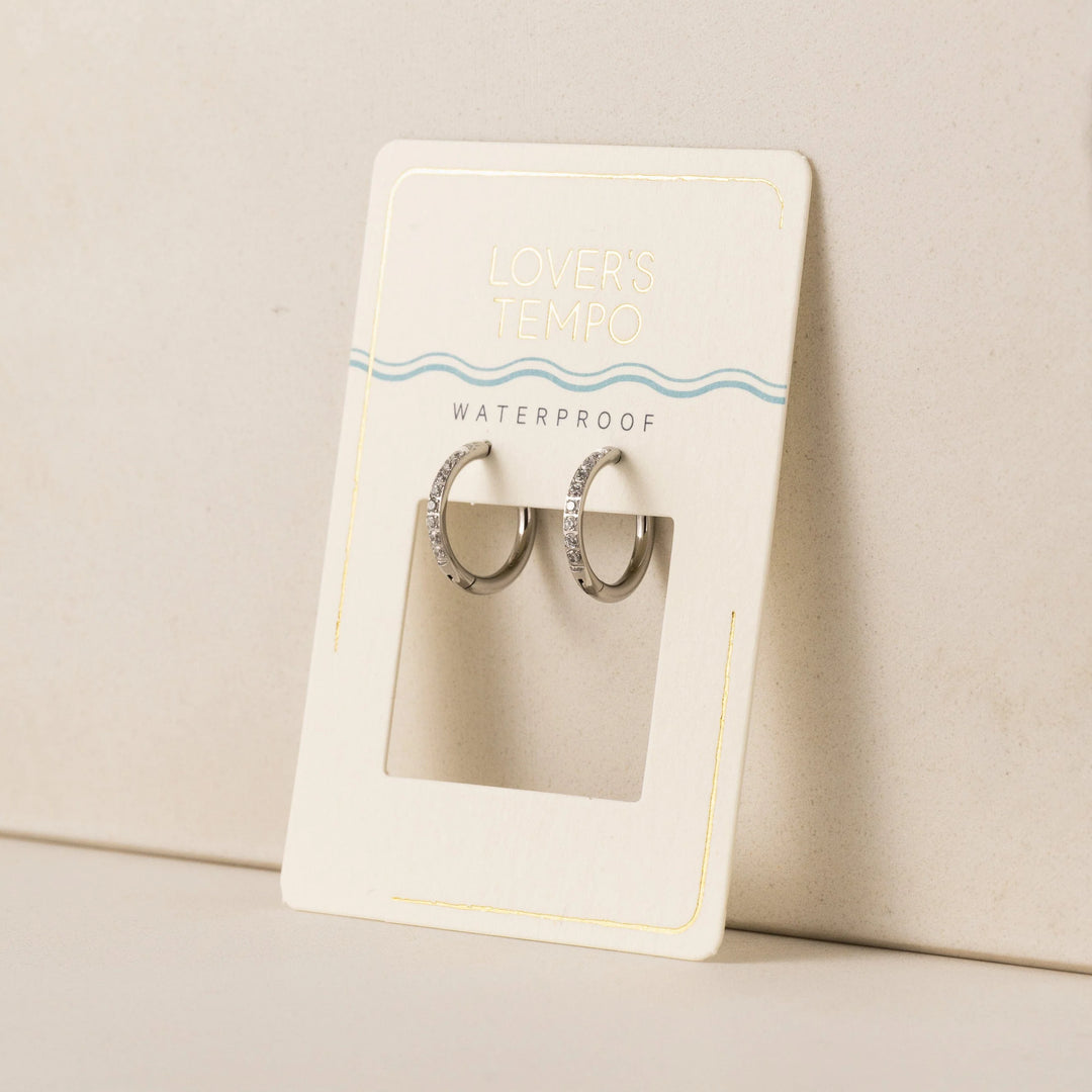 Pair of silver hoop earrings in a clear display case on a beige card with 'Waterproof' text.