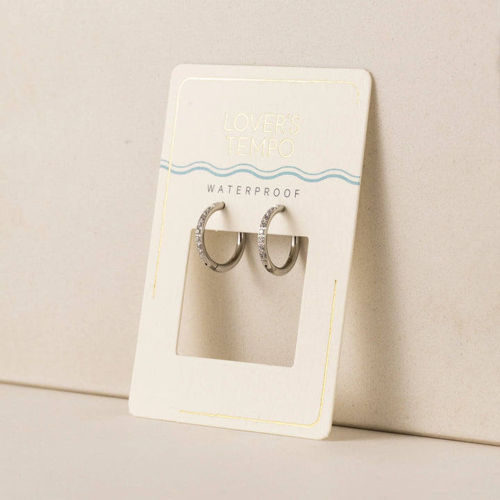 Pair of silver hoop earrings in a clear display case on a beige card with 'Waterproof' text.