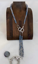 Necklace with blue beads and silver clasp on a wooden stand