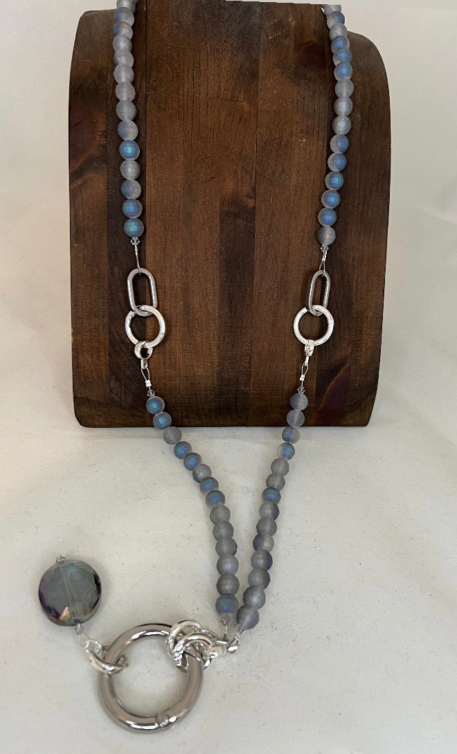 Necklace with gray beads and silver clasp on a wooden stand