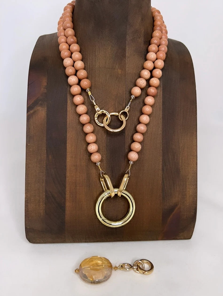 Necklace with wood beads and gold rings on a wooden stand