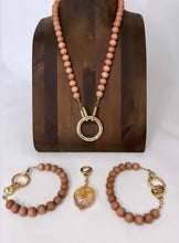wood bead Jewelry set including a necklace, bracelet, and pendant on a wooden stand with a white background.