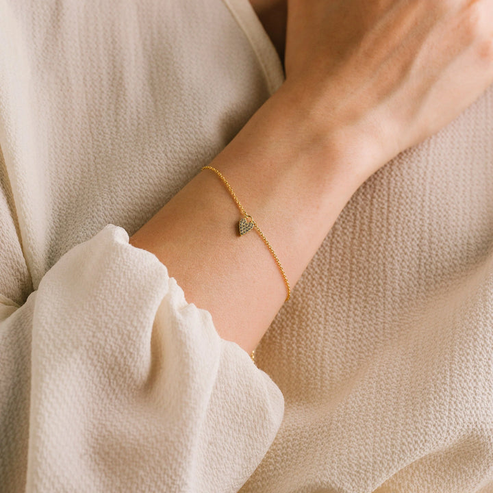 Gold bracelet on a wrist with a neutral background