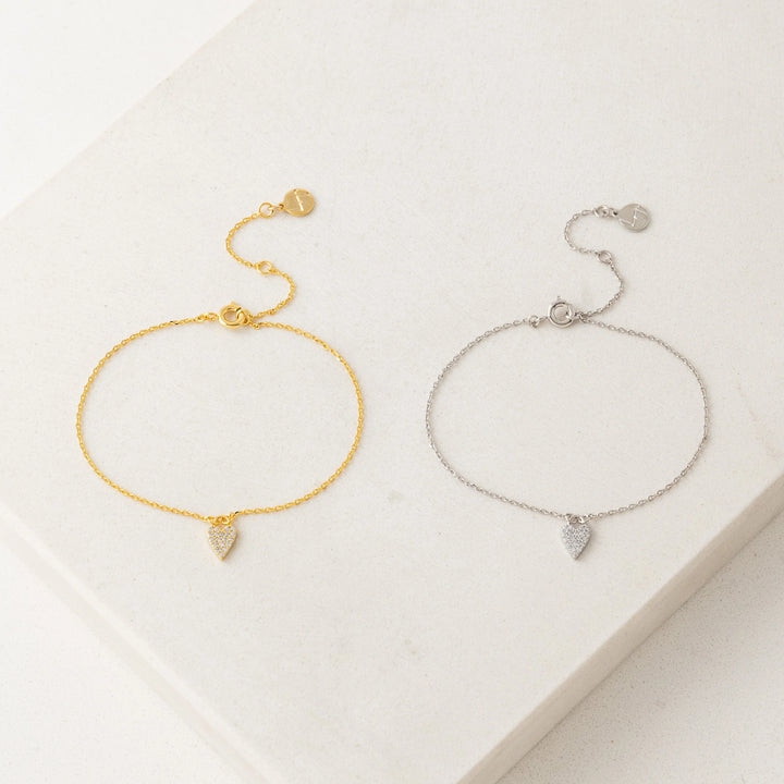 Gold and silver bracelets with heart-shaped charms on a light background