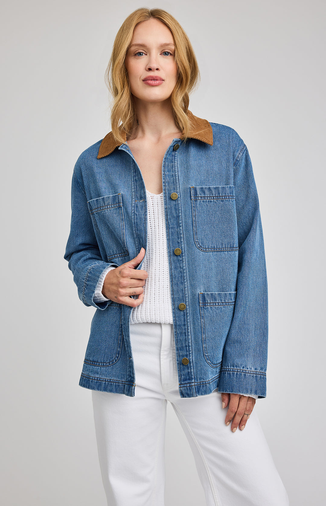 Woman wearing a blue denim barn  jacket with a brown collar on a white background