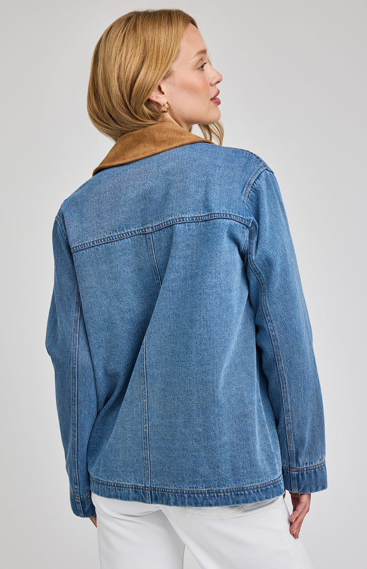 Woman wearing a blue denim barn jacket on a plain background
