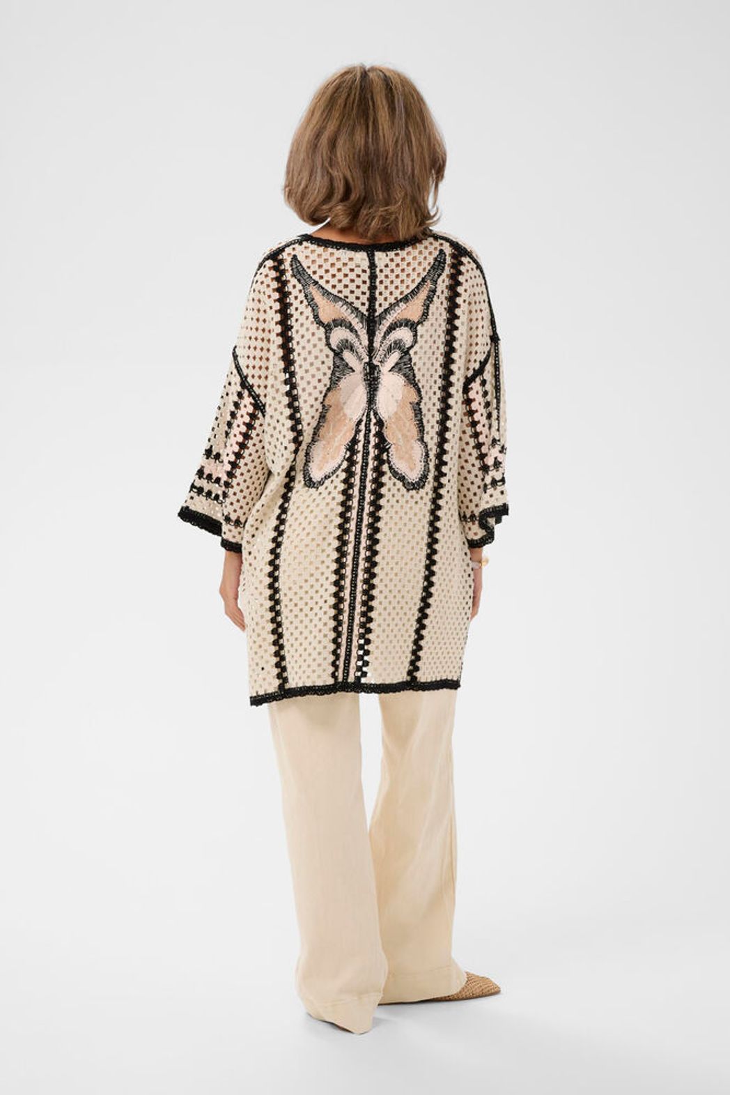 Cream Free Fly crochet kimono featuring an open-front design with intricate crochet patterns and lightweight, breathable fabric with butterfly motif on back..