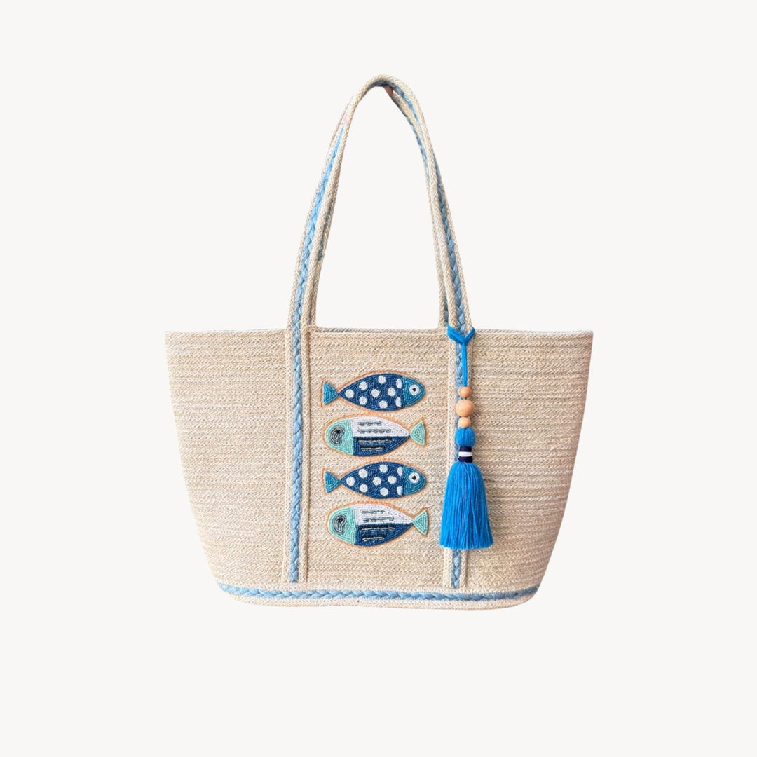 Blue beaded fish design on a jute bag with tassels by Canadian line Pokoloko, showcasing intricate beadwork and natural jute material, perfect for summer, vacation, beach, and travel.