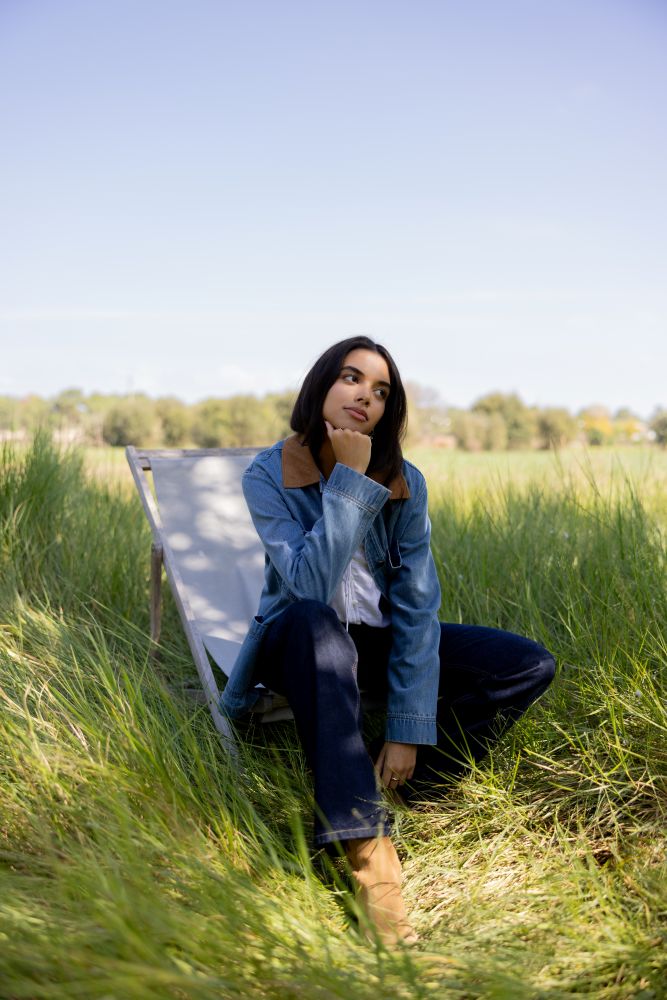 Woman sitting on a chair in a grassy field with trees in the background