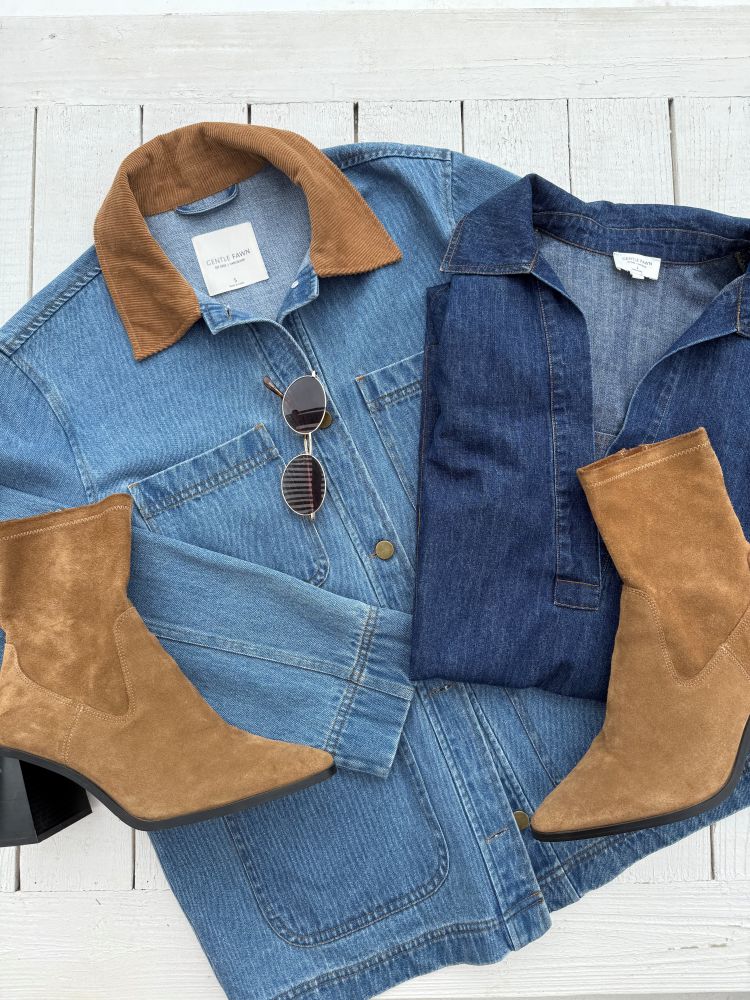Blue denim barn jacket with brown collar and cuffs, paired with brown suede boots on a white wooden surface.