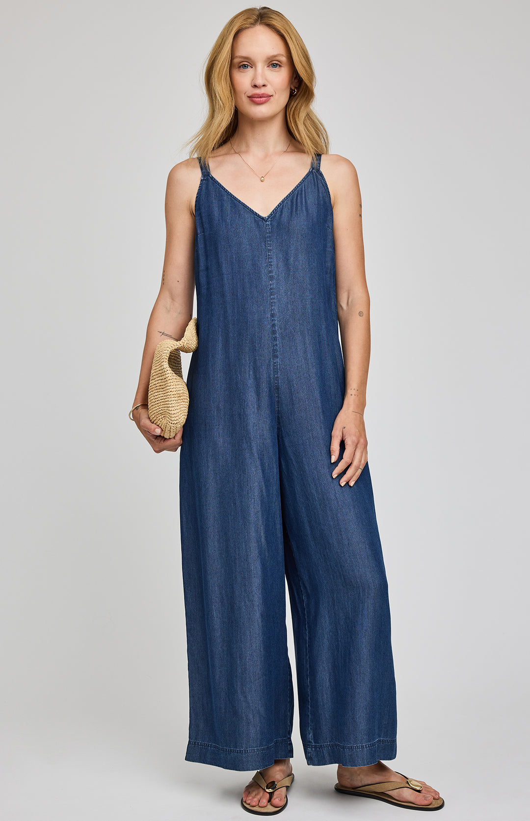 Gentle Fawn Cambry denim jumpsuit romper with adjustable straps and side pockets, styled casually on a model.