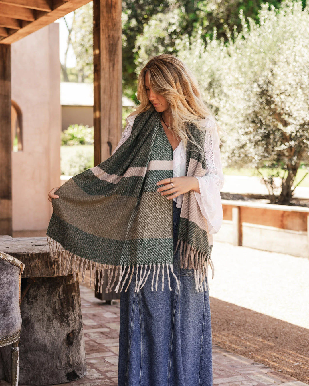 Woman holding a green plaid scarf outdoors