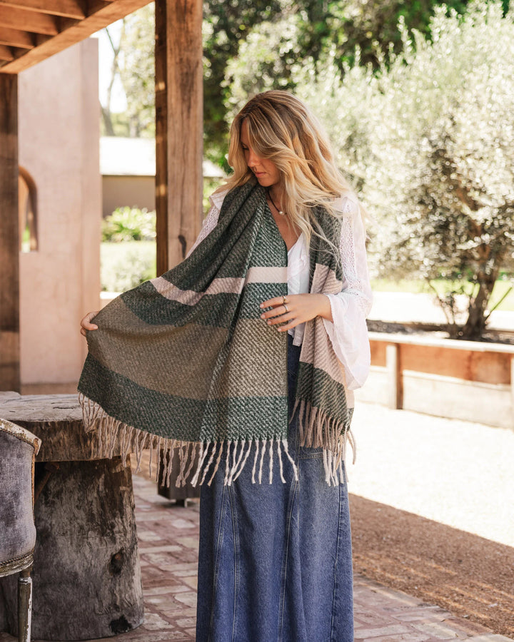 Woman holding a green plaid scarf outdoors