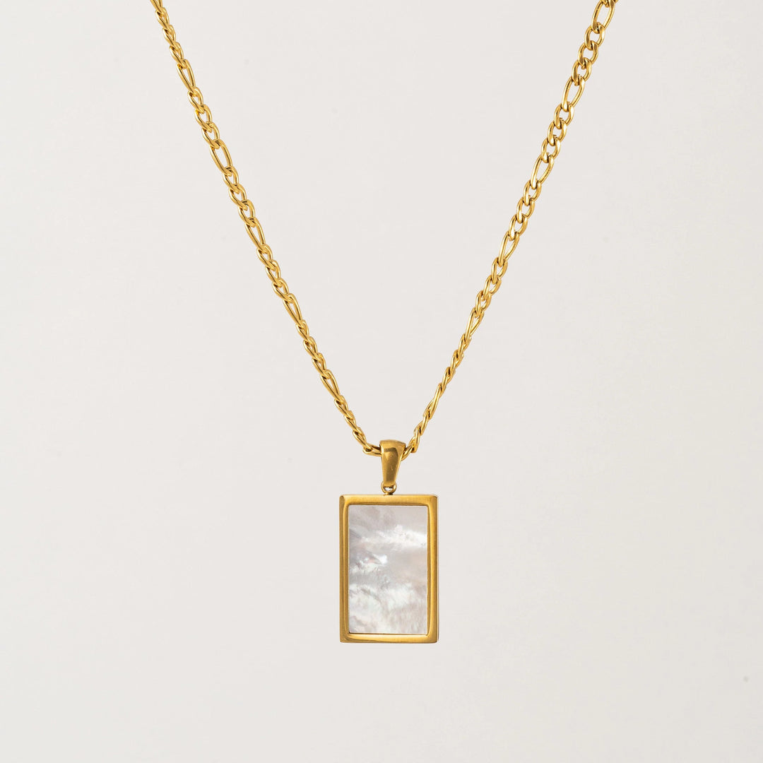 Gold necklace with a rectangular pendant on a light gray background
