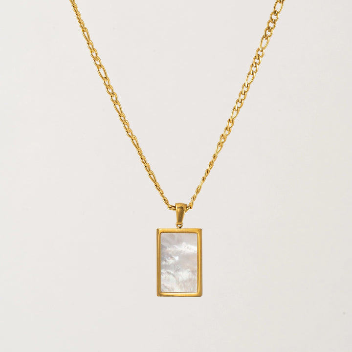 Gold necklace with a rectangular pendant on a light gray background