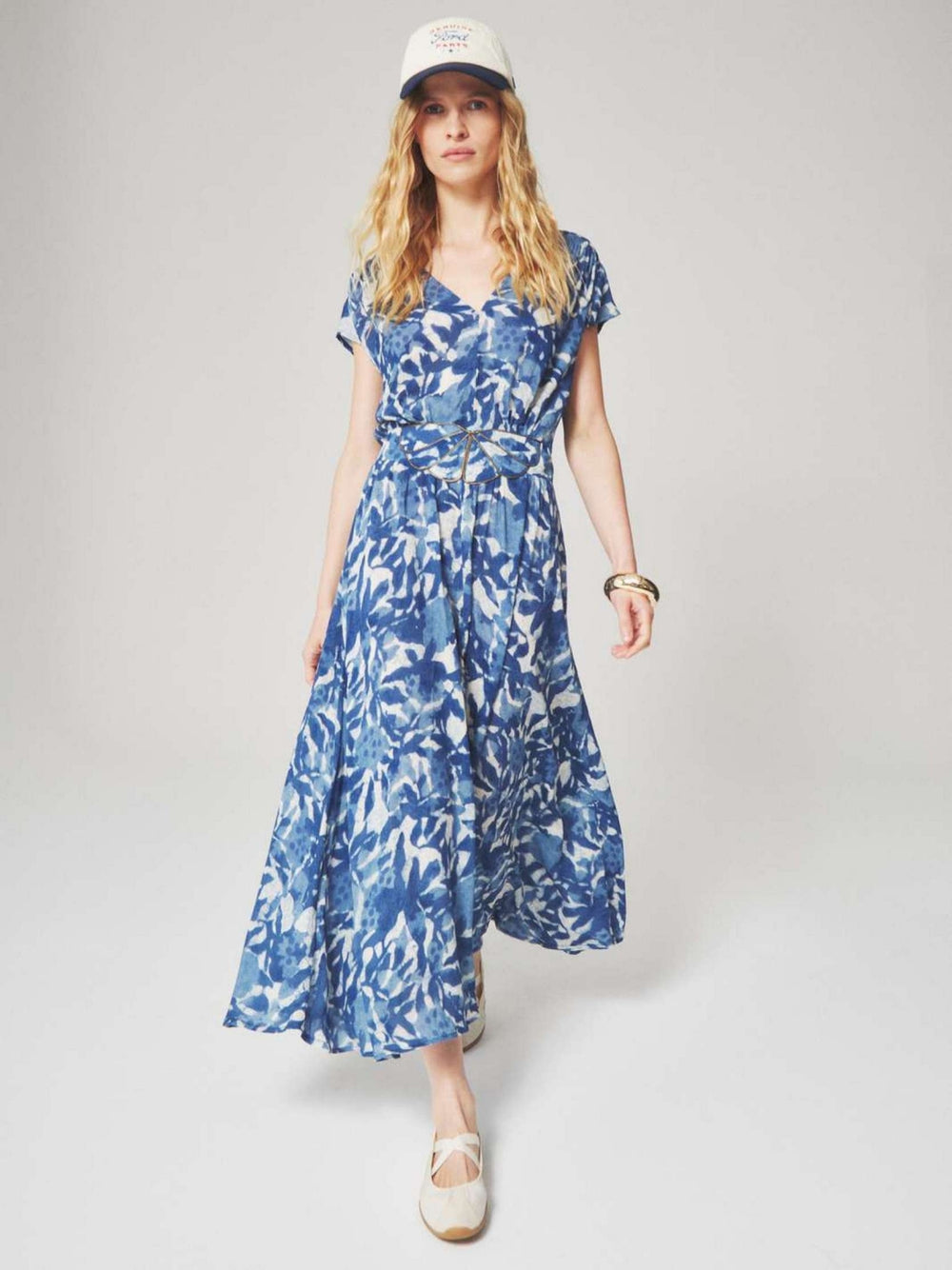 Woman wearing a blue and white floral patterned midi dress with a summer style for semi floral and event occasions.