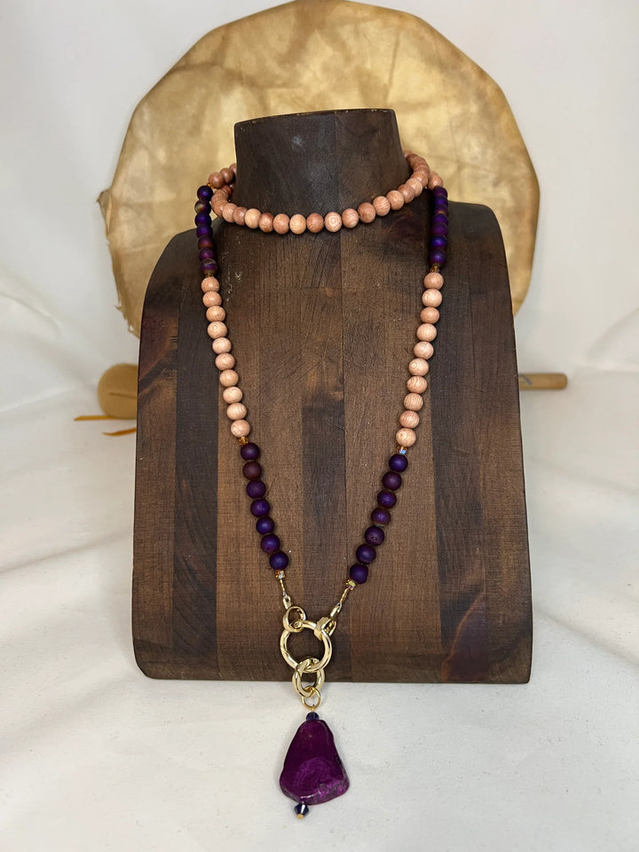 Necklace with rosewood and purple beads on a wooden stand