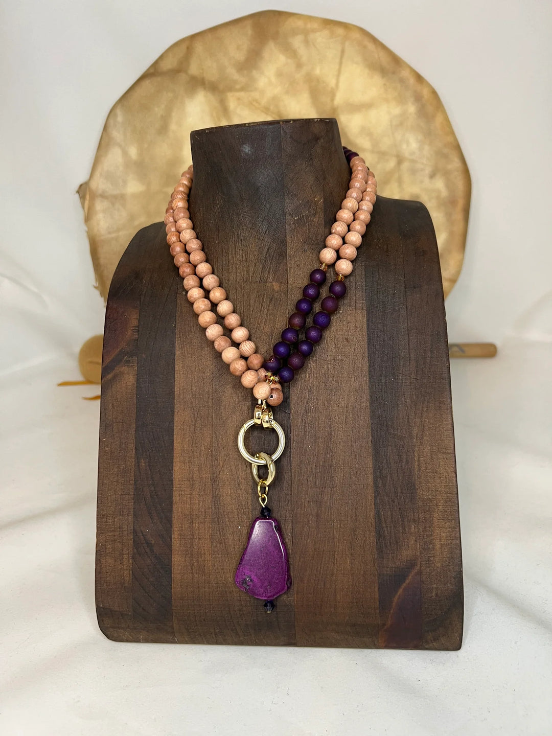 Necklace with rosewood and purple beads on a wooden stand