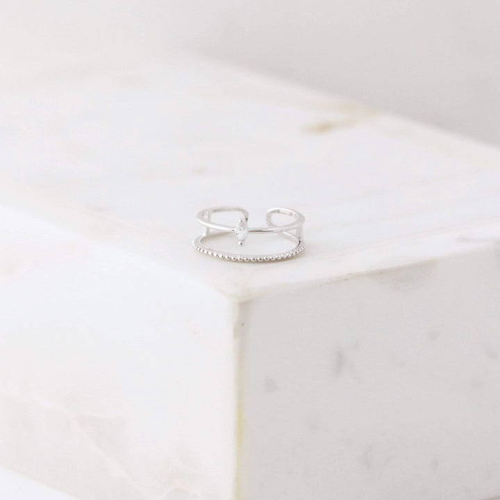Silver double band ring with a small cubic zirconia diamond  on a white marble surface