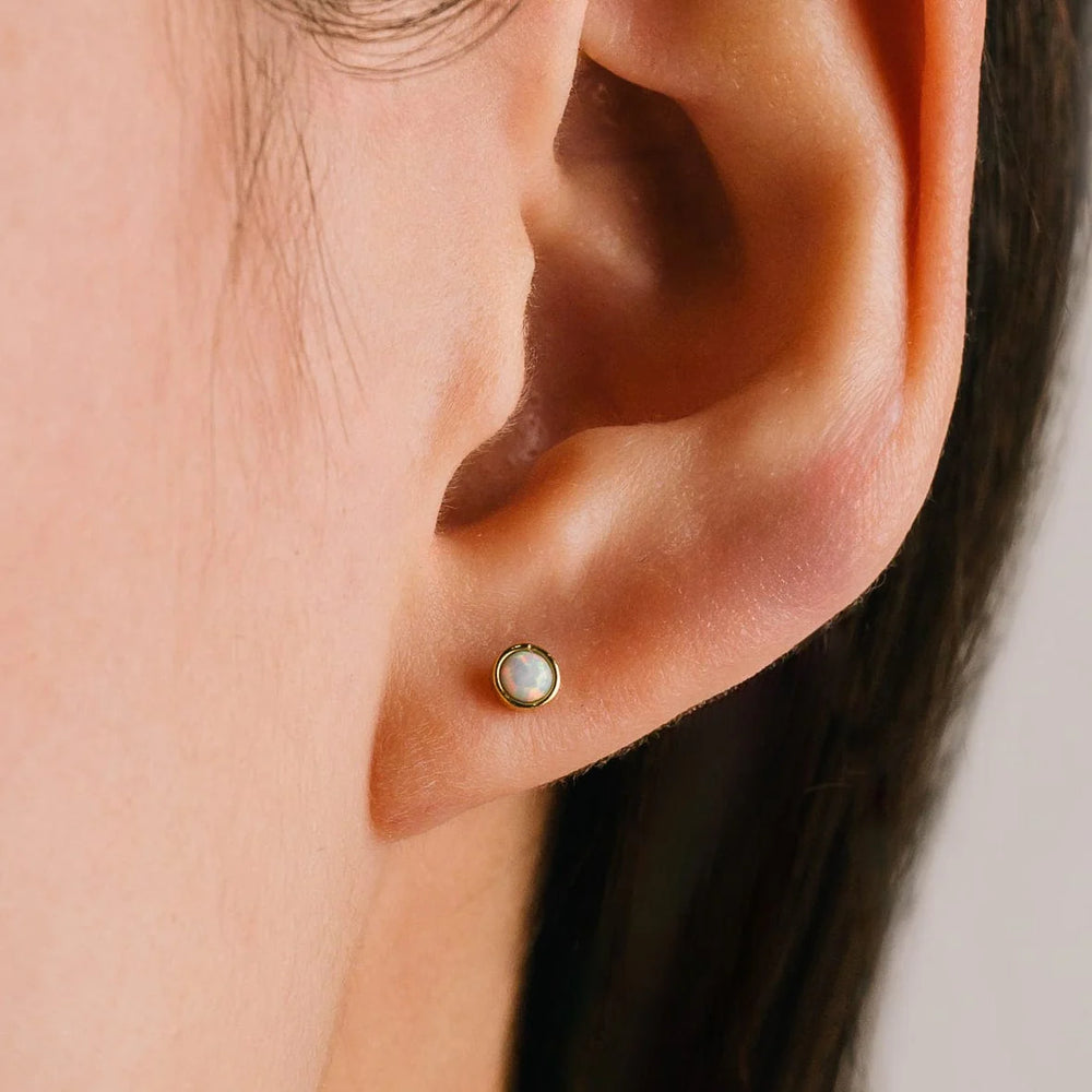 Close-up of an ear wearing a gold earring with a gemstone.