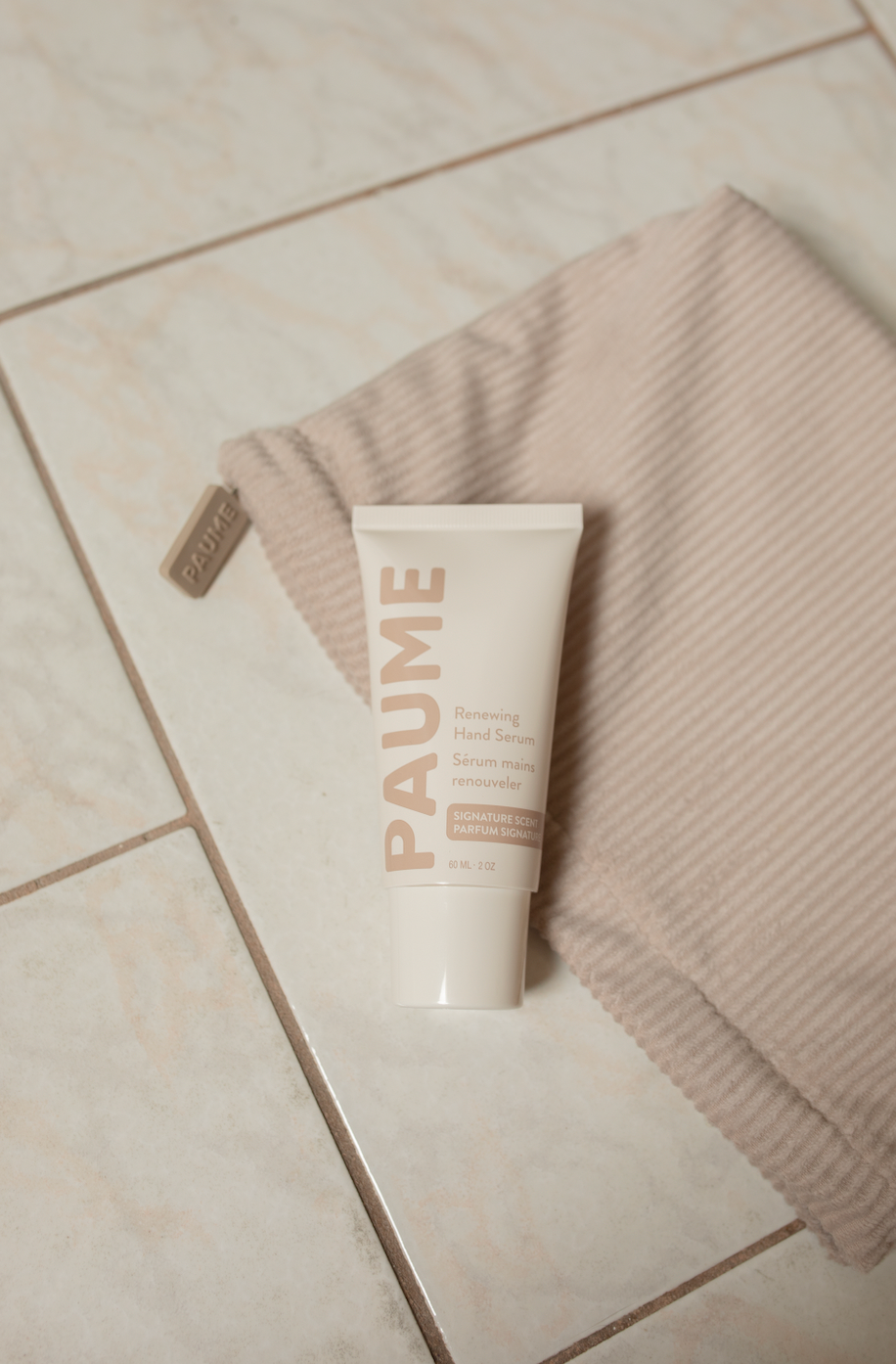 Tube of PAUME Paume anti aging hand serum on a towel on a tiled floor