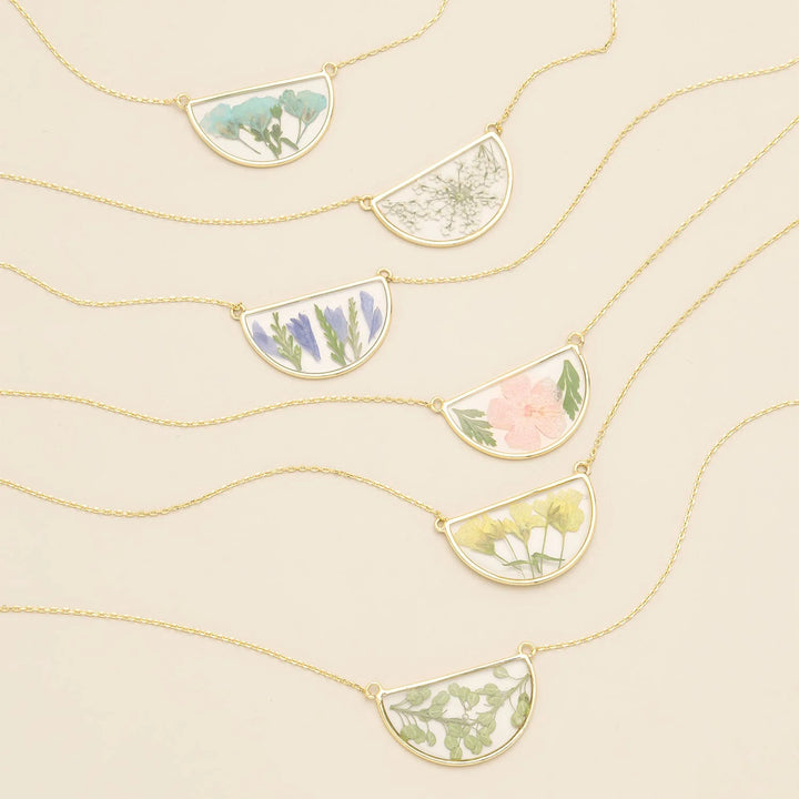 Scout pressed flower necklace featuring a delicate semi circle pendant with real pressed flowers in a glass charm.