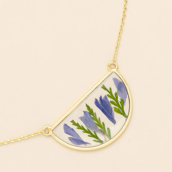 Scout pressed flower necklace featuring a delicate circle pendant with colorful pressed flowers on a gold chain.