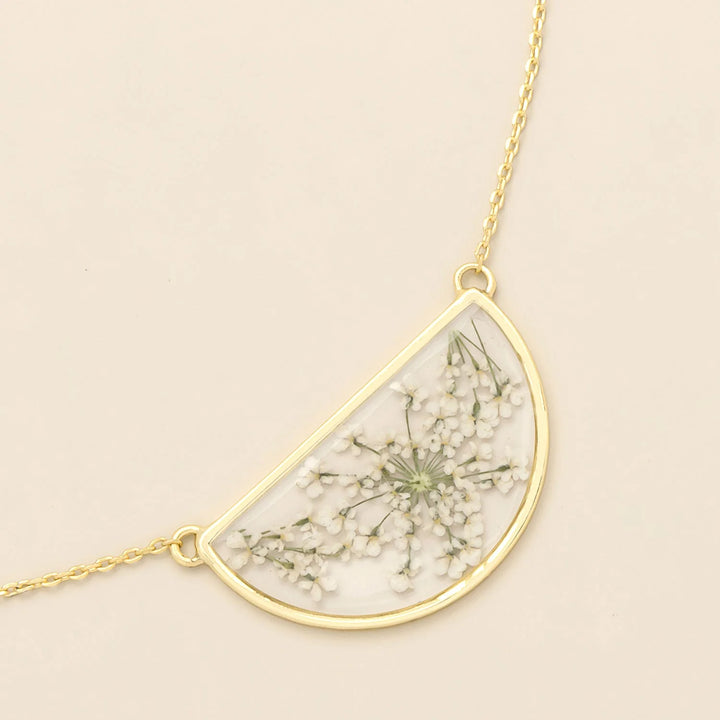 Scout pressed flower necklace featuring a delicate round pendant with real preserved flowers on a gold chain.
