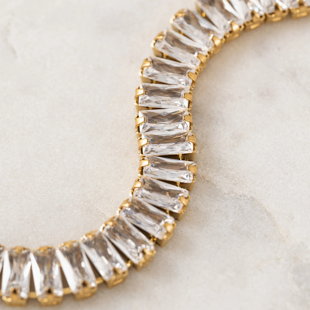 Gold and clear gemstone bracelet on a light background