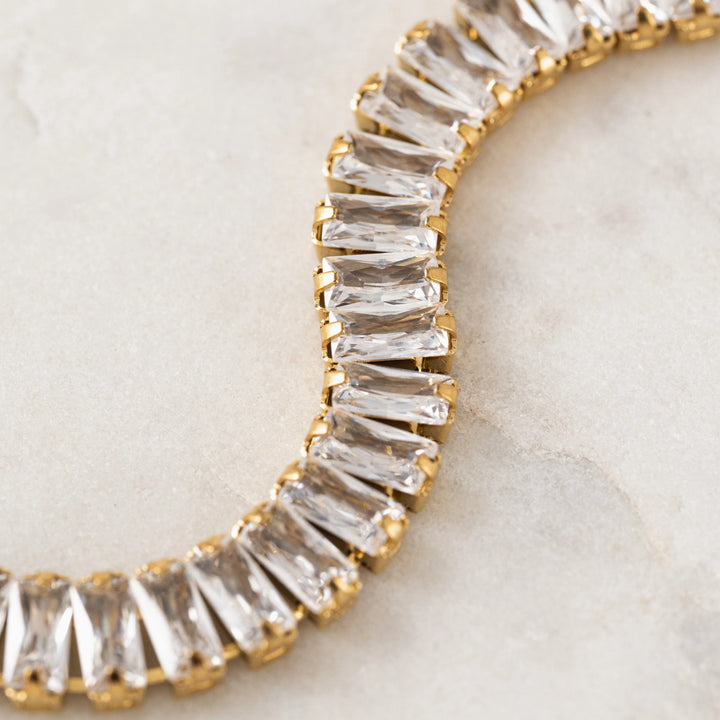 Gold and clear gemstone bracelet on a light background