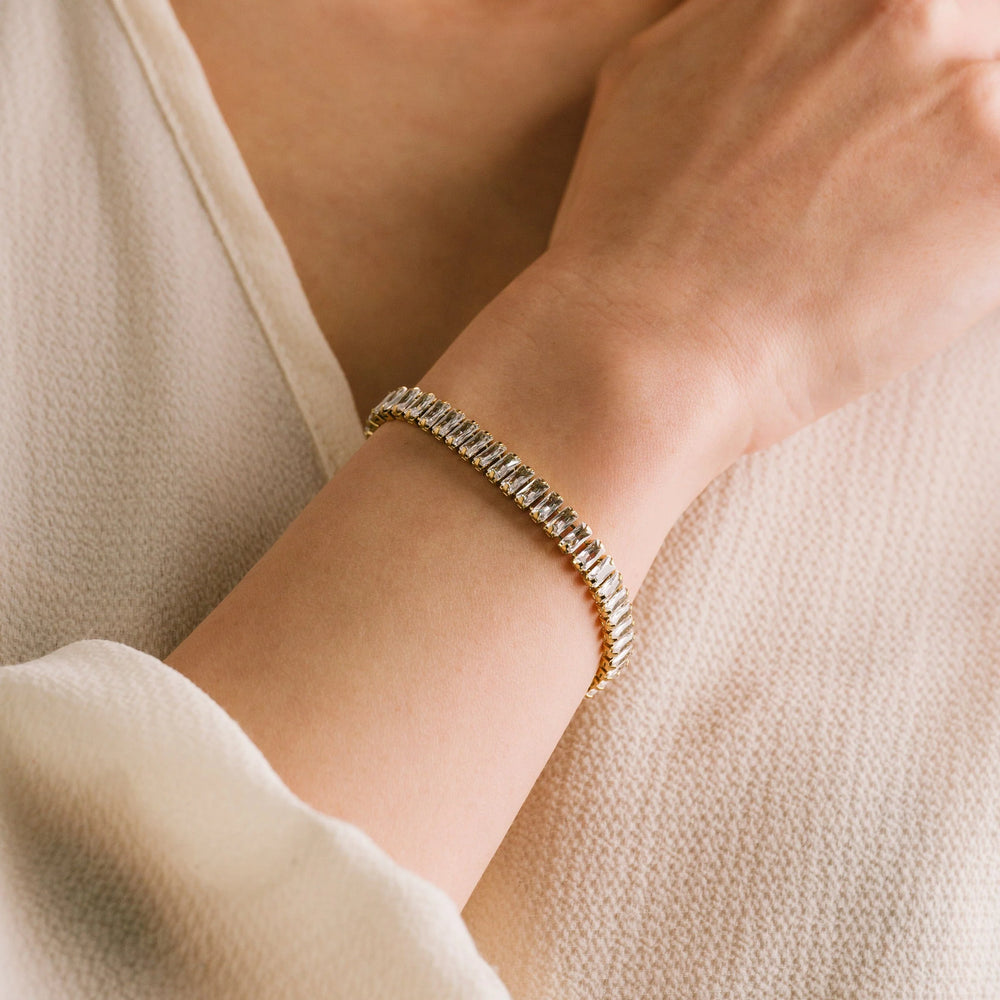 Gold bracelet on a wrist with a neutral background