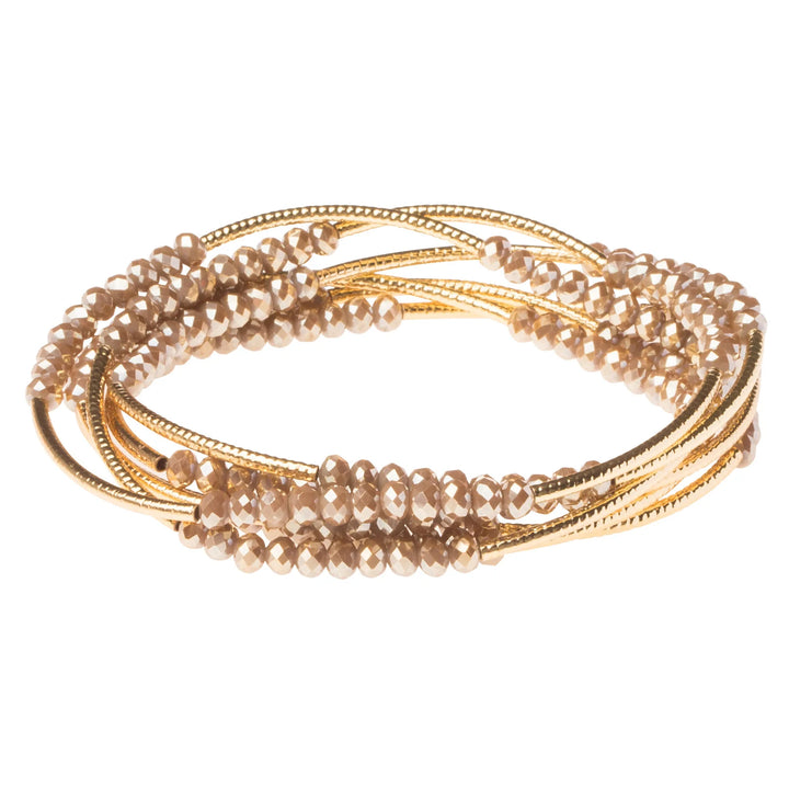 Gold Scout Curated Wears wrap bracelet featuring oyster-colored beads and adjustable design, styled as a versatile accessory.