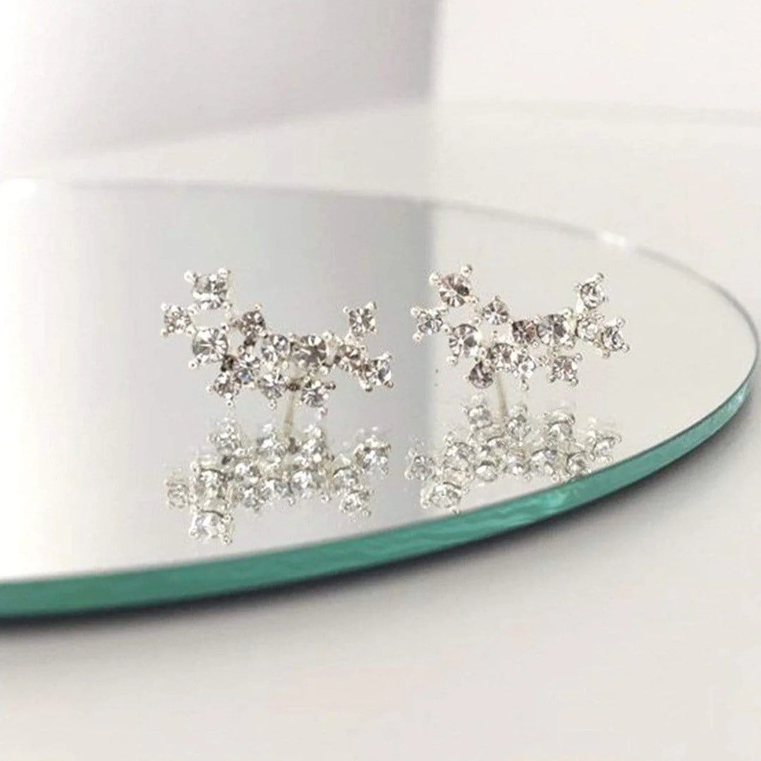 Silver and crystal climber earrings on a glass surface