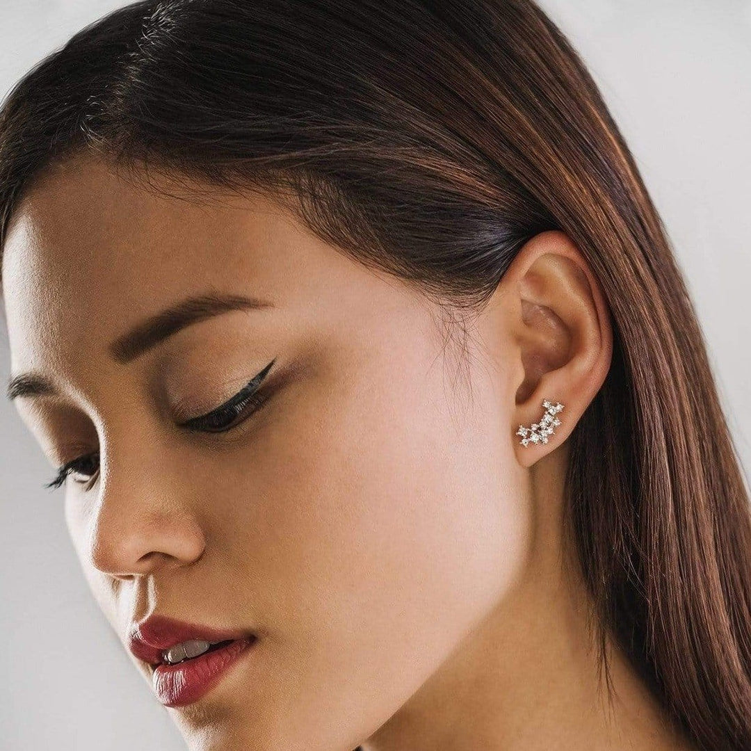 Close-up of a woman wearing a star-shaped earring with a neutral background