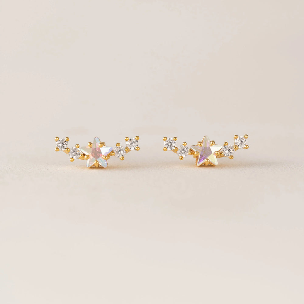Pair of gold and silver star-shaped earrings on a beige background
