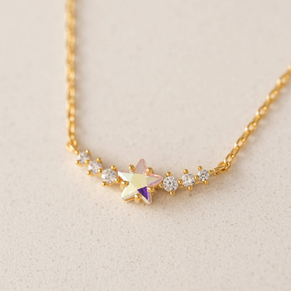 Gold necklace with a star-shaped pendant on a beige background