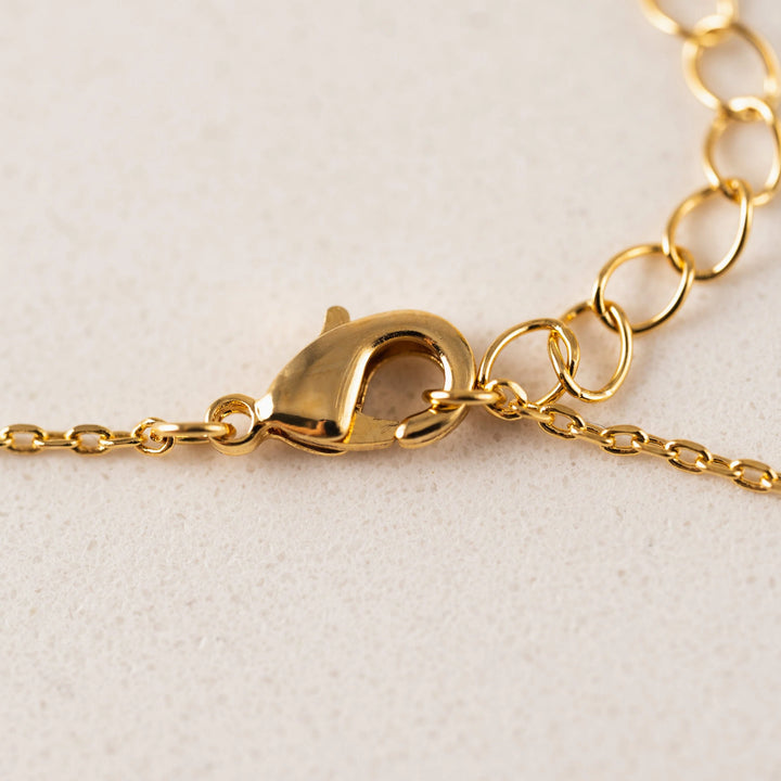 Close-up of a gold chain with clasp on a beige background