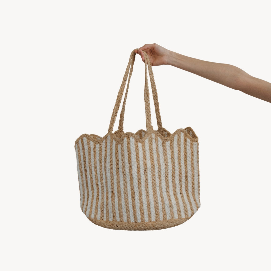 Hand holding a striped woven bag on a white background