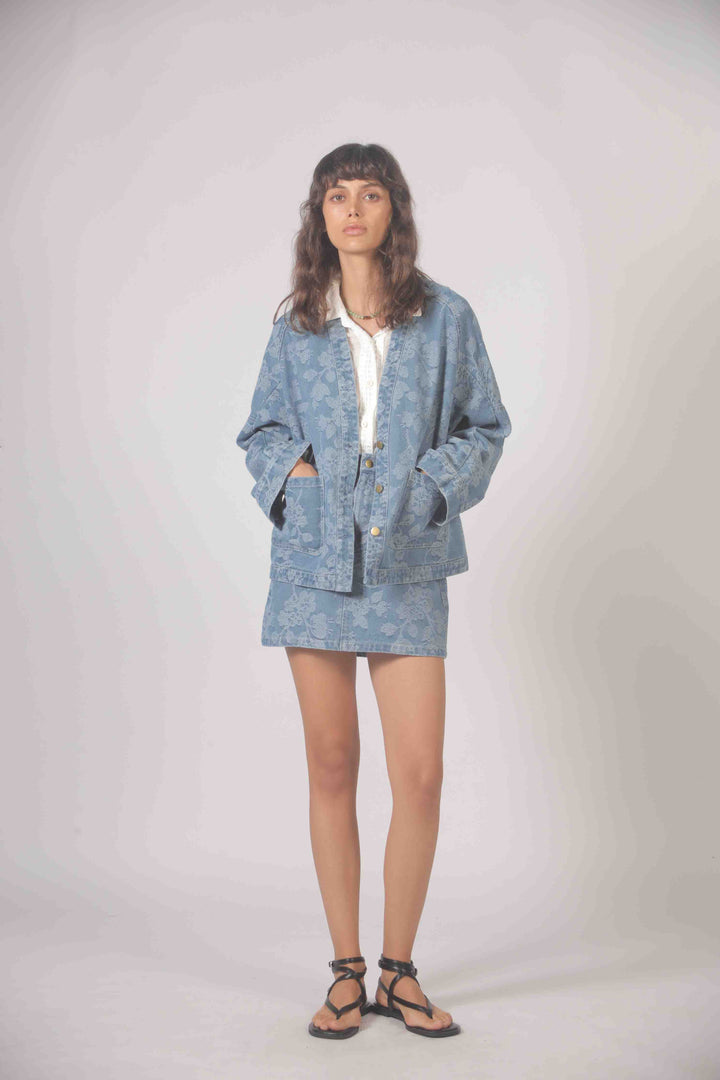 Embroidered denim jacket by The Korner featuring intricate floral designs and classic blue denim fabric.